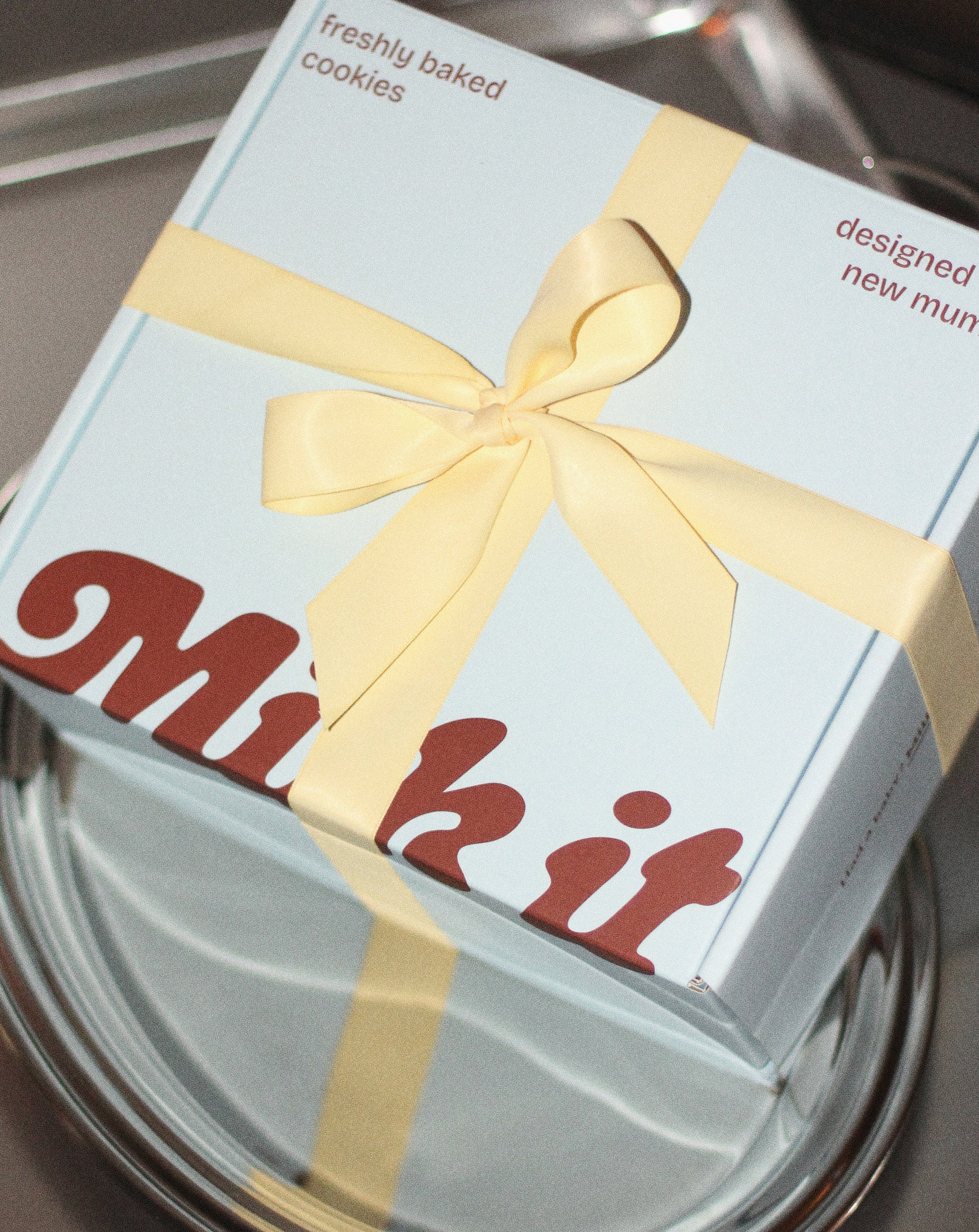 a box of Milk it cookies wrapped in a yellow bow on a silver platter. 