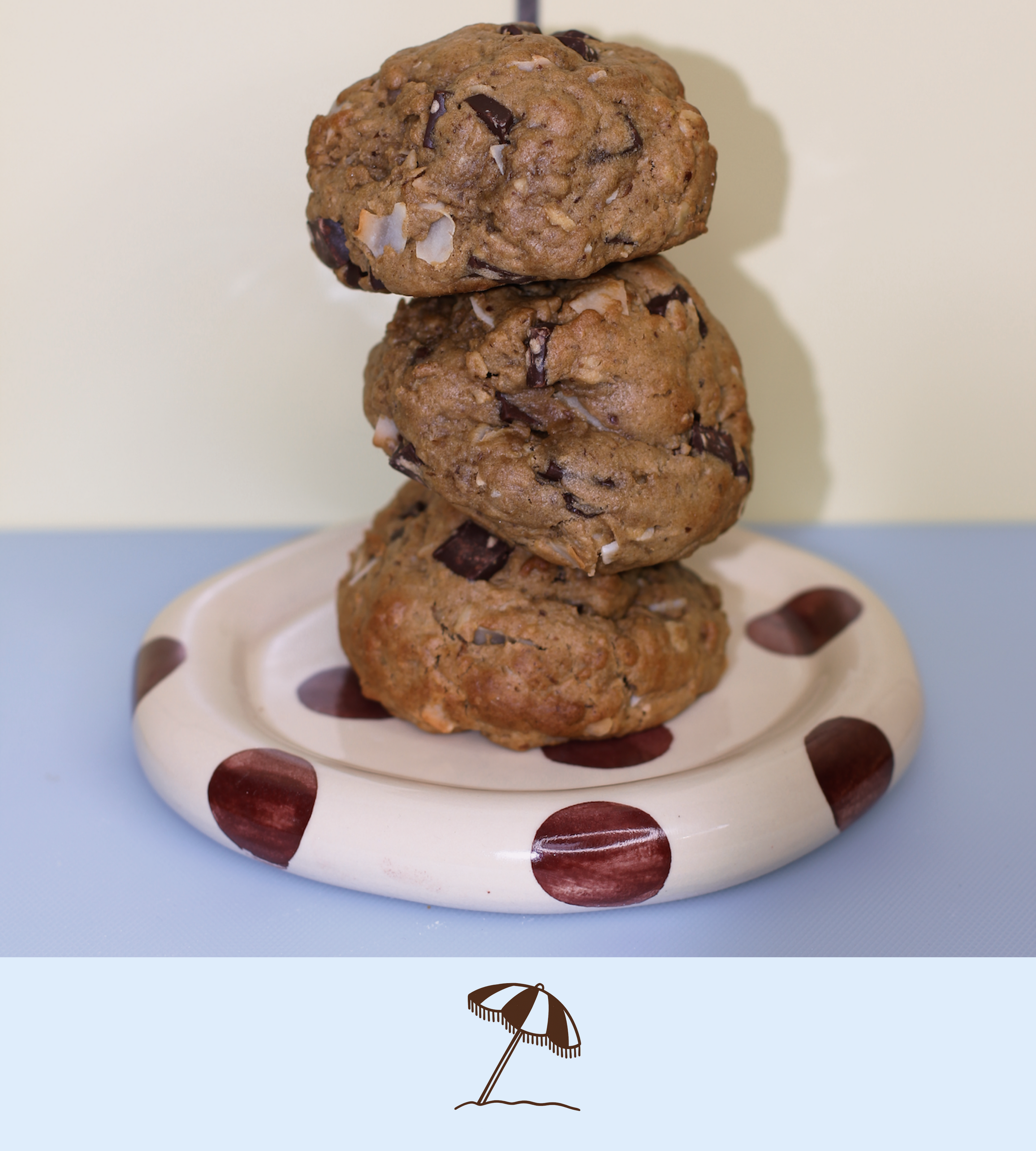 Stack of dark chocolate and coconut lactation cookies on a polka dot plate with a plain background