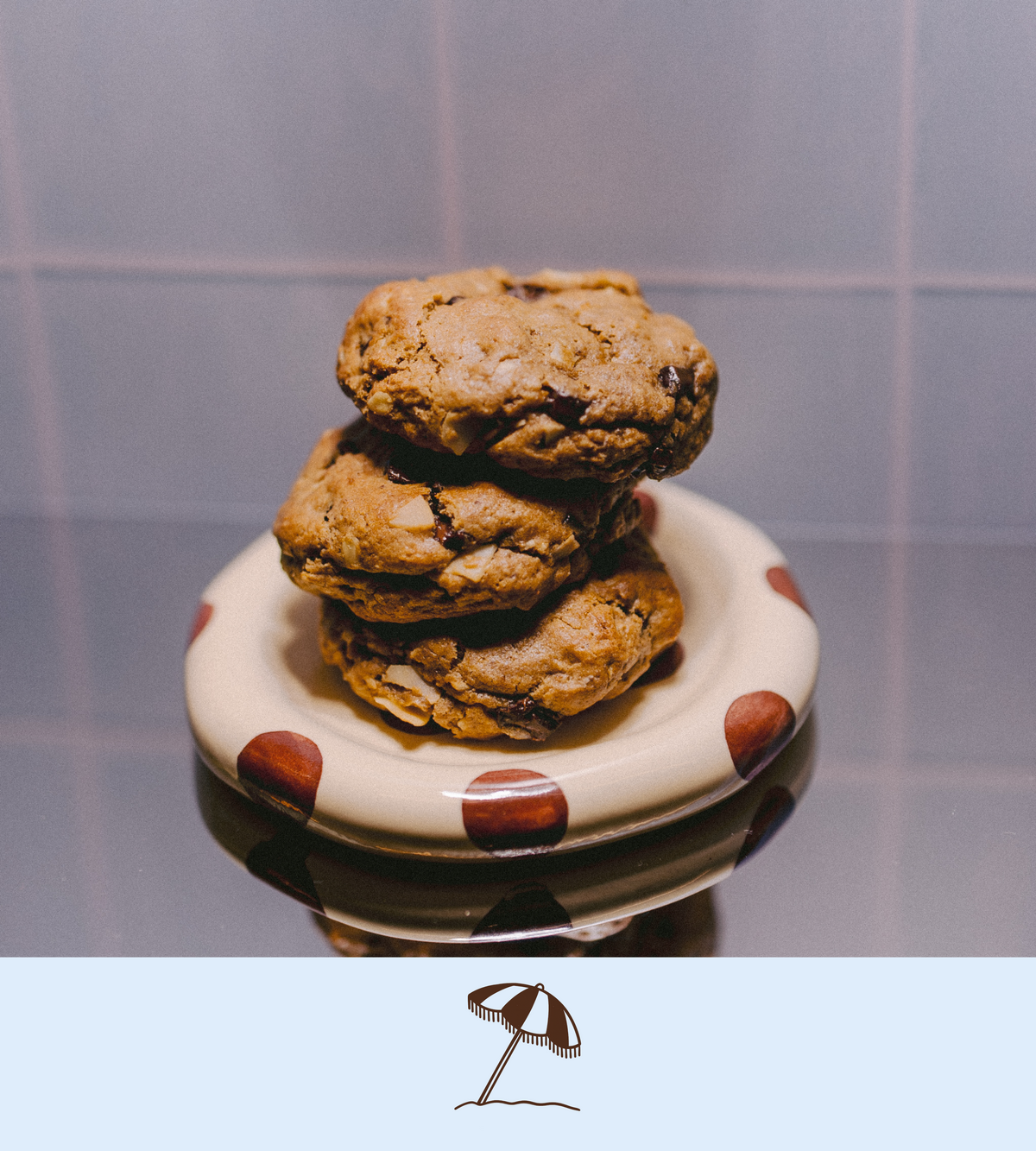 Stack of dark chocolate and coconut lactation cookies on a polka dot plate with a plain background