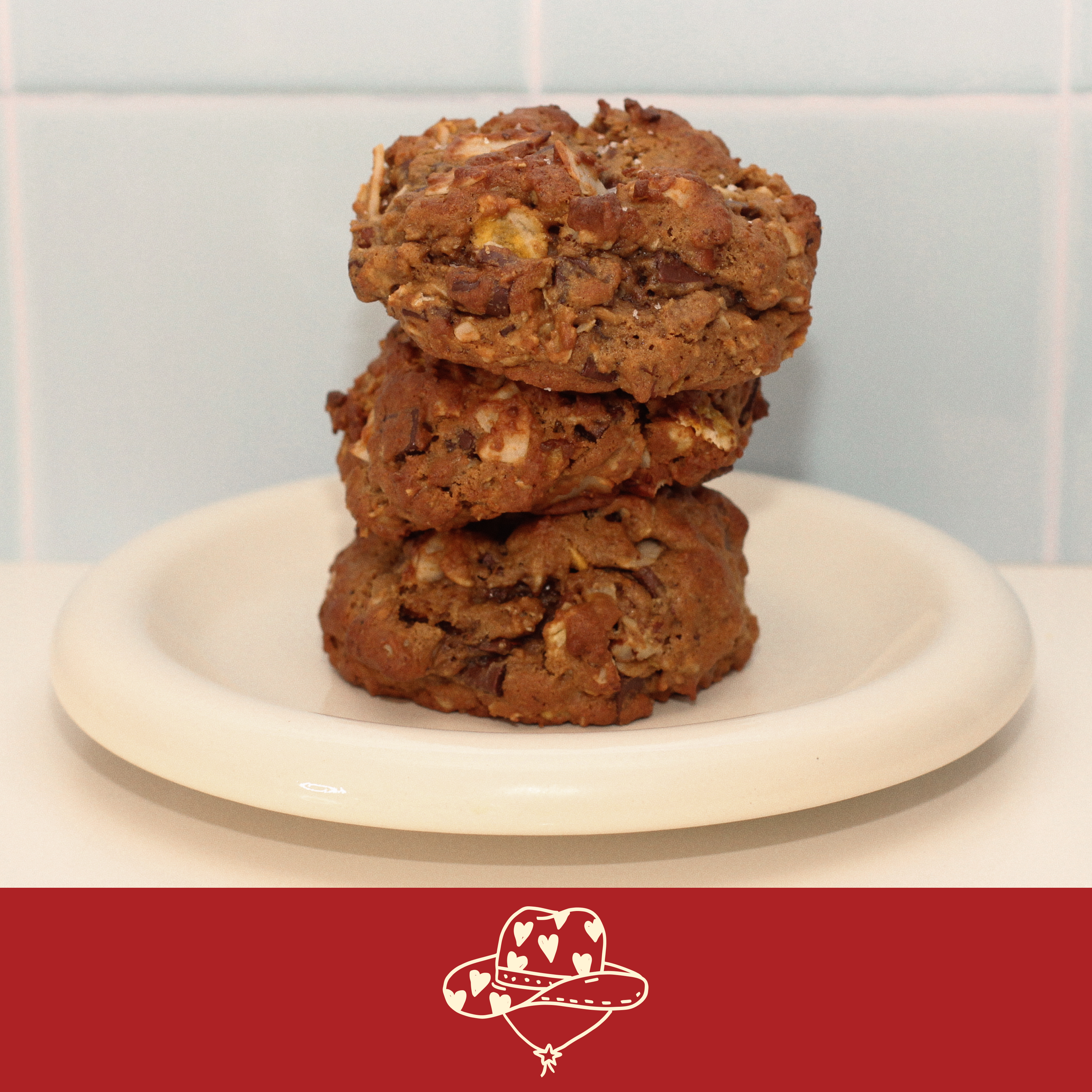 Cowgirl lactation cookie with pecan, coconut, cornflake, and dark chocolate on a white plate 
