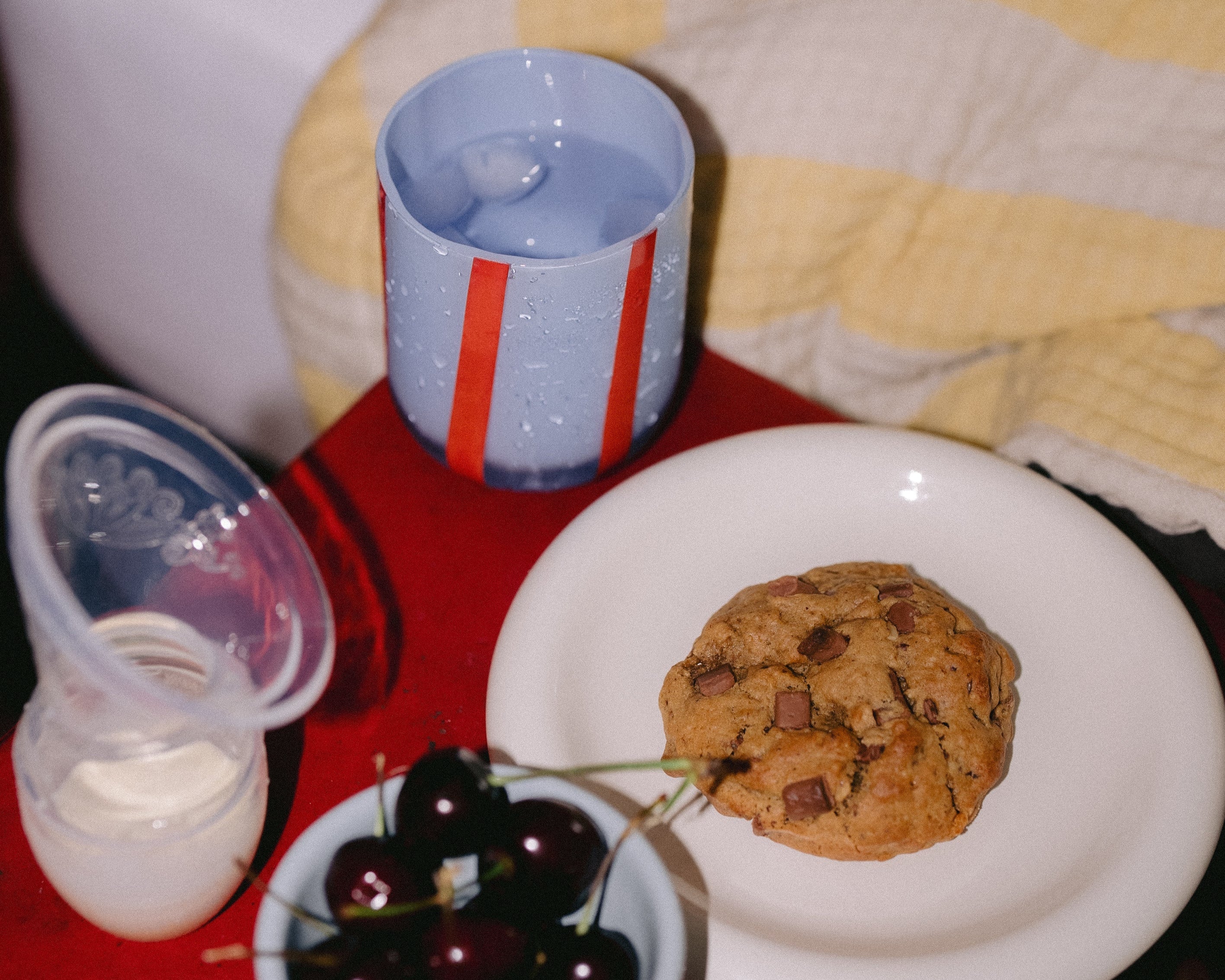 Bedside scene with lactation cookie, Haakaa pump, and snacks — styled for a breastfeeding mum in the postpartum period