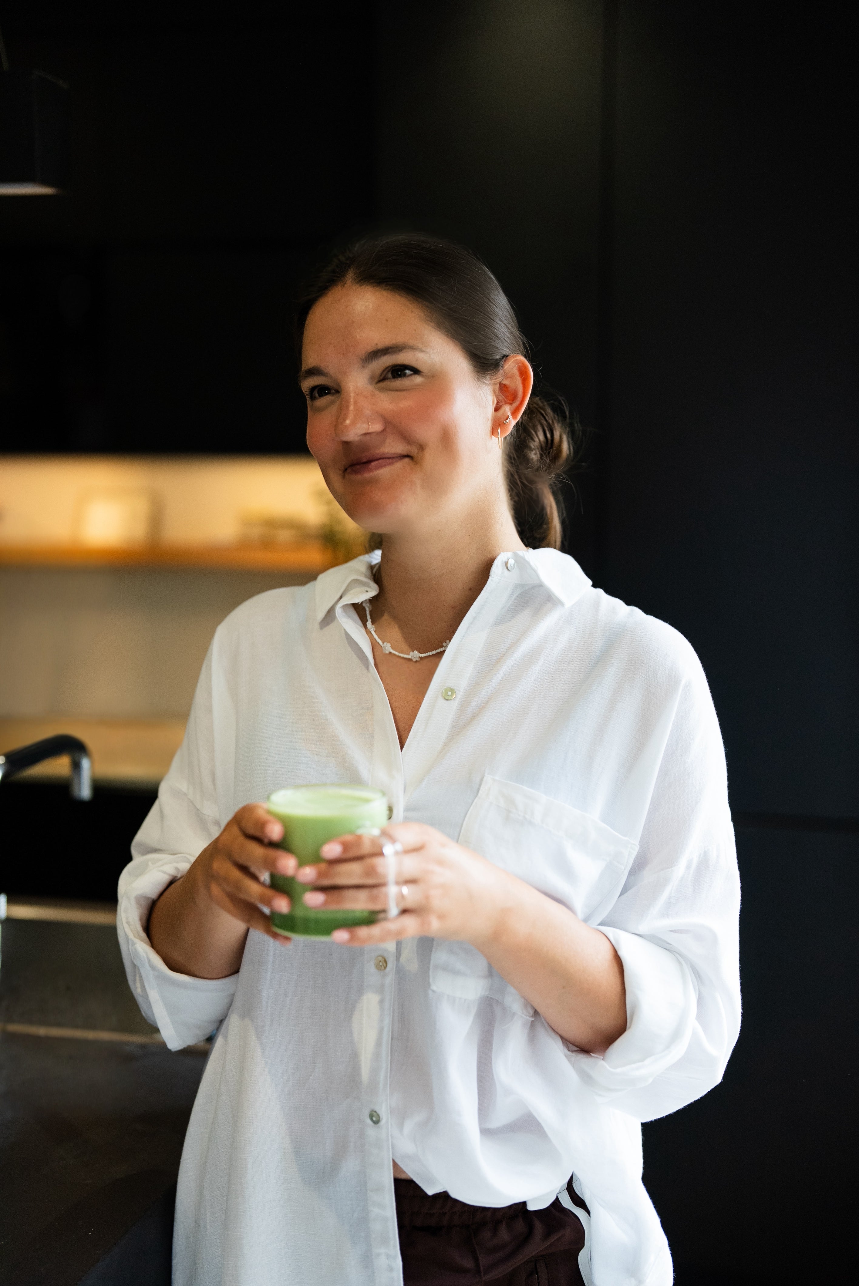 Mel, founder of Milk it, smiling warmly while holding a matcha latte. She’s wearing a white linen top and radiates a calm, supportive energy.