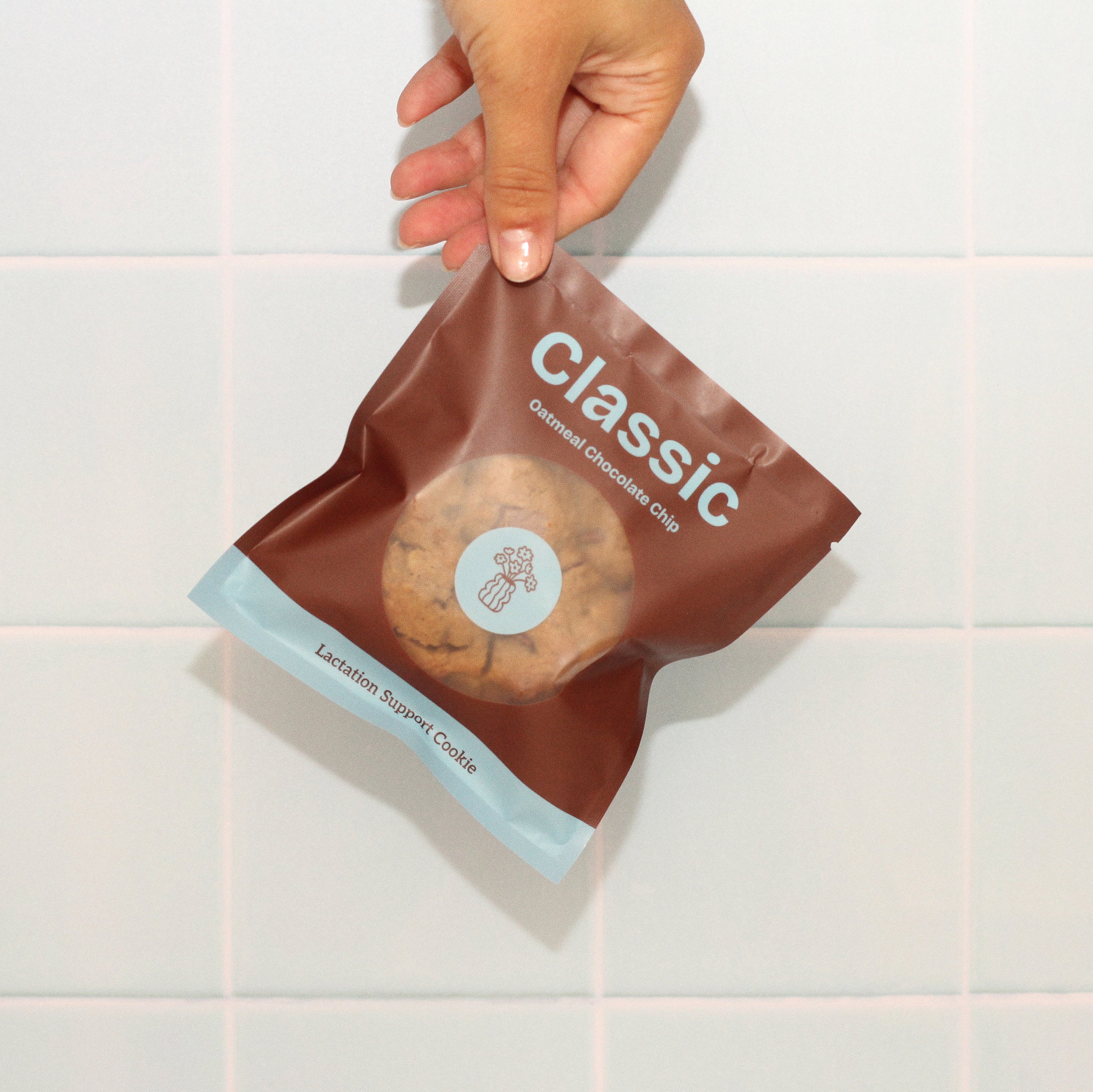 Close-up of Milk it lactation cookie in the classic oatmeal chocolate chip flavour with branded bag – breastfeeding snack made with oats, flaxseed, and brewer’s yeast