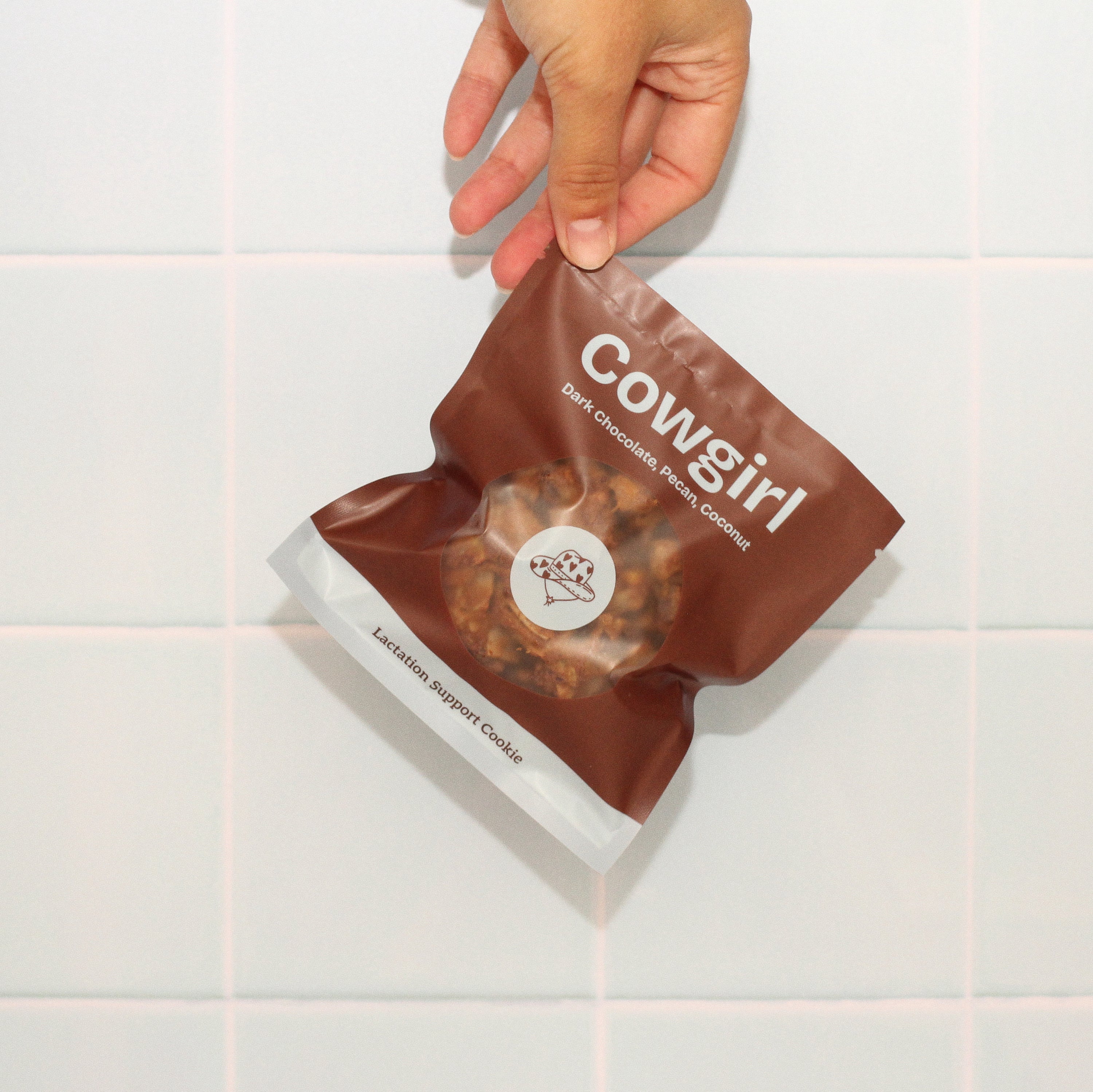 Close-up of Milk it lactation cookie with branded bag in cowgirl pecan coconut dark chocolate flavour – breastfeeding snack made with oats, flaxseed, and brewer’s yeast