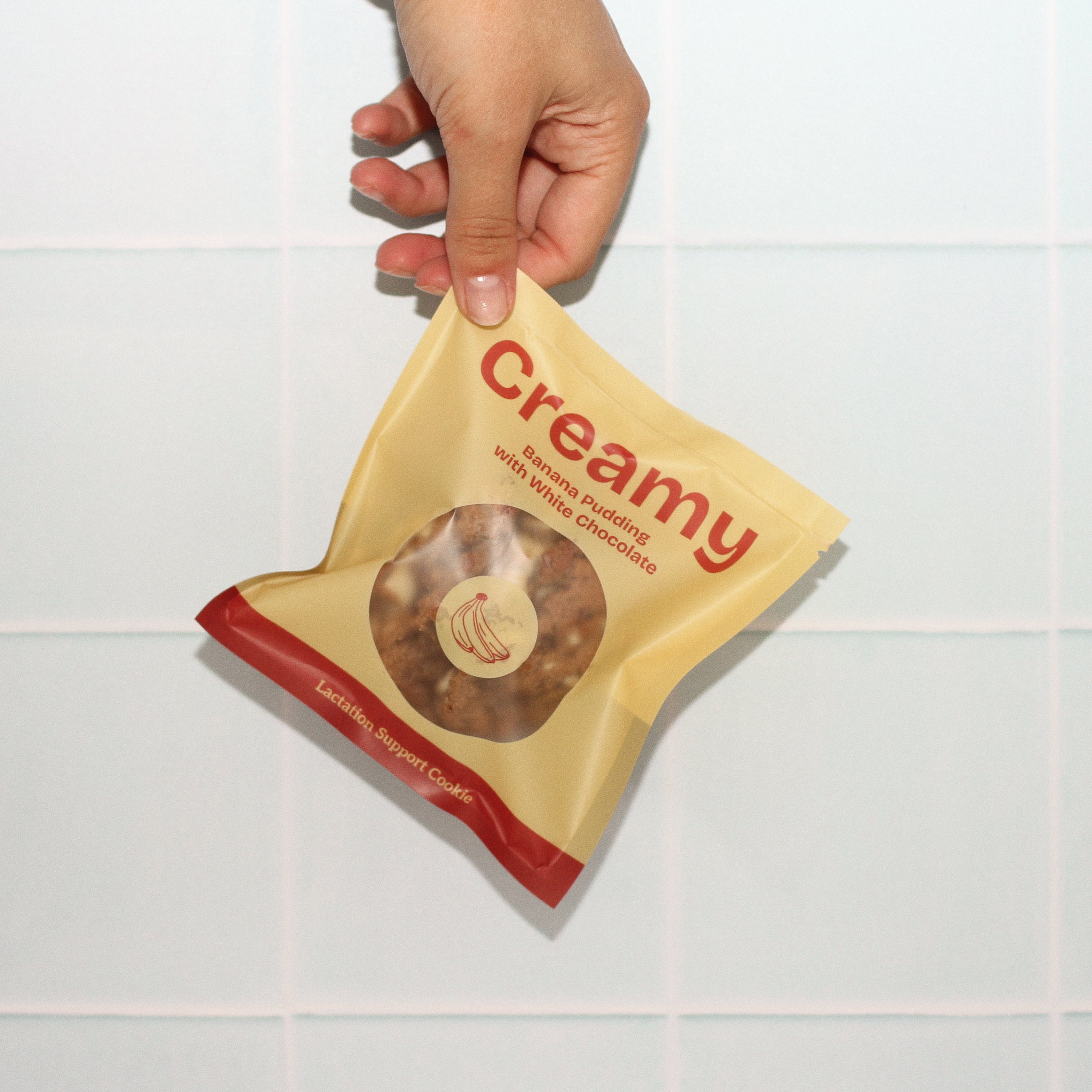 Close-up of Milk it lactation cookie with branded bag in creamy banana pudding flavour – breastfeeding snack made with oats, flaxseed, and brewer’s yeast