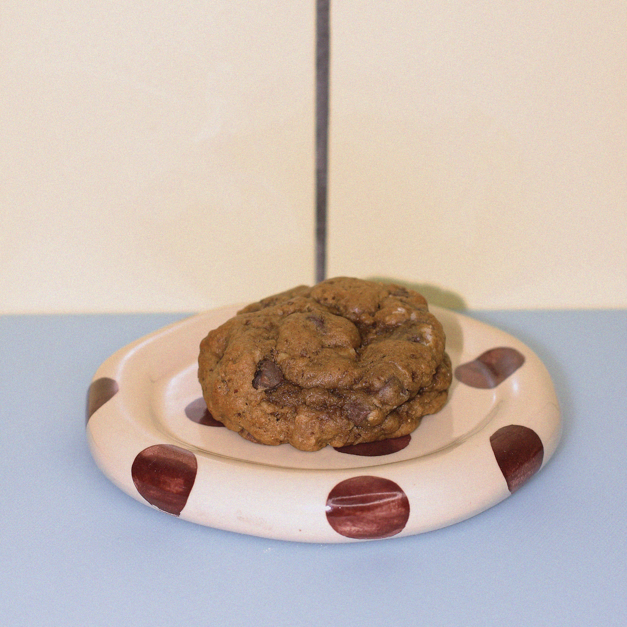 classic oatmeal chocolate chip lactation cookie against a butter yellow tiled wall.
