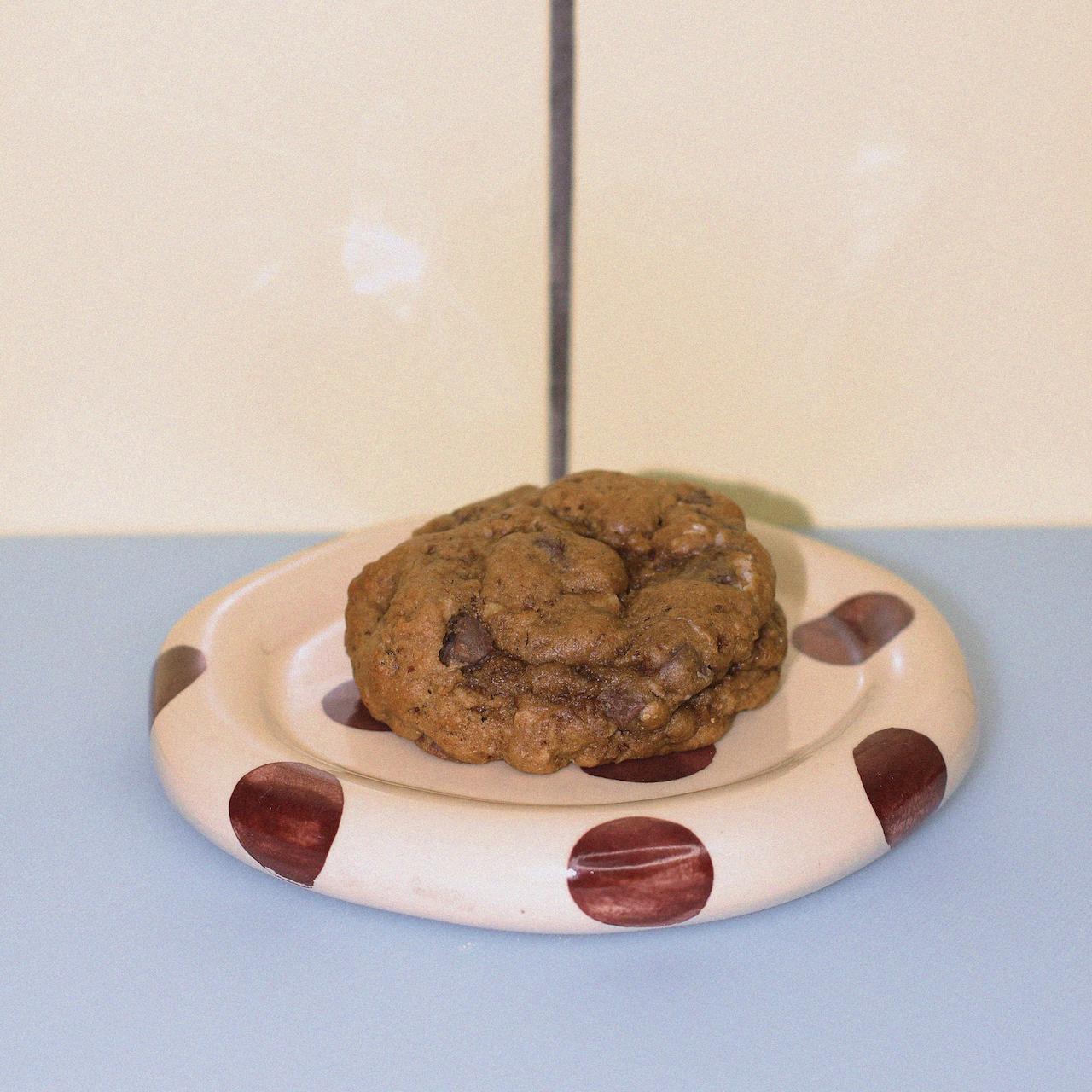 classic oatmeal chocolate chip lactation cookie against a butter yellow tiled wall.