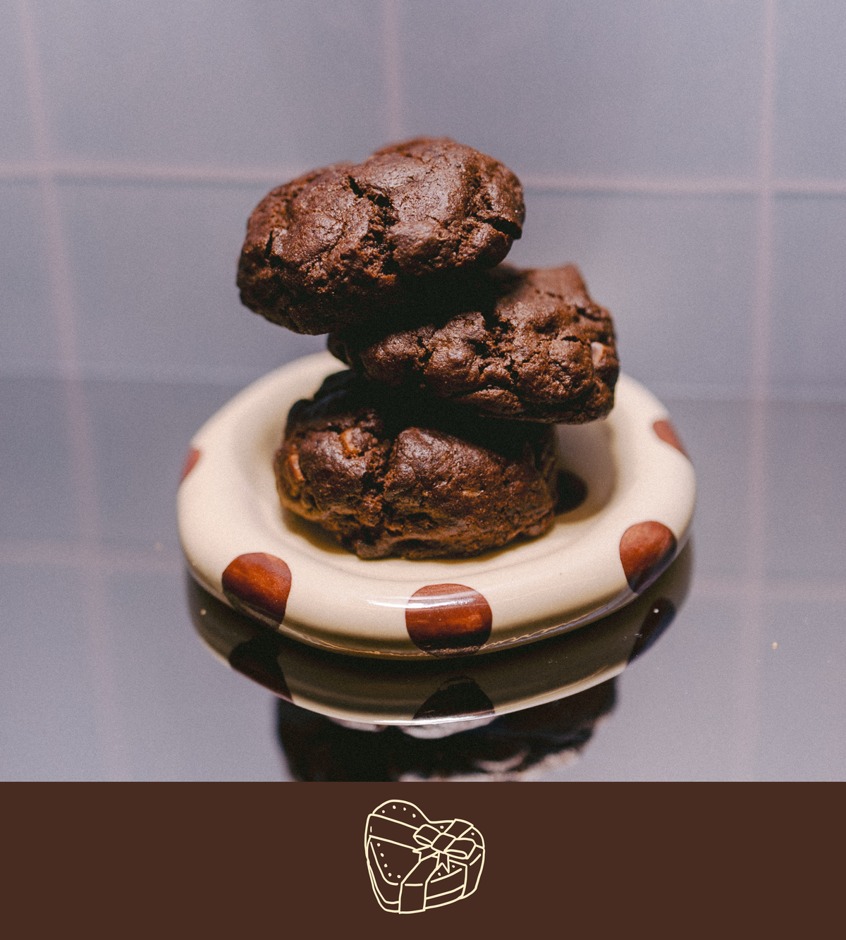 Stack of triple chocolate chunk lactation cookies on a polka dot plate with a plain background