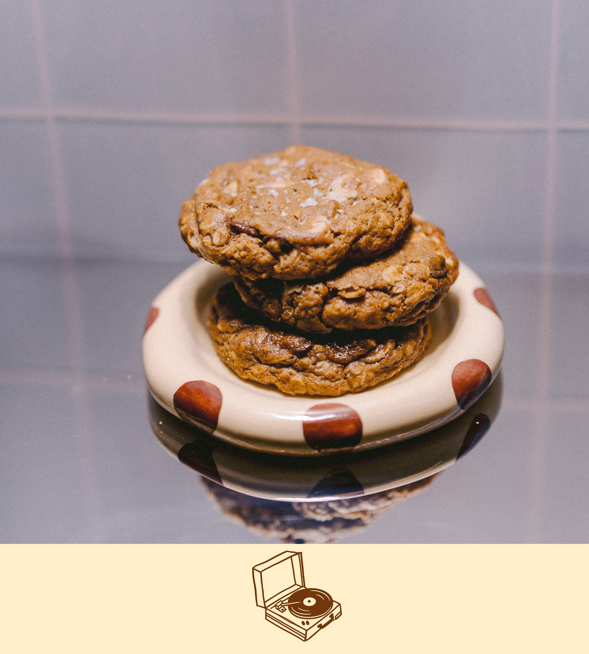 a stack of vegan latctation cookies on a polka dot plate with dark chocolate and blonde oat chocolate throughout