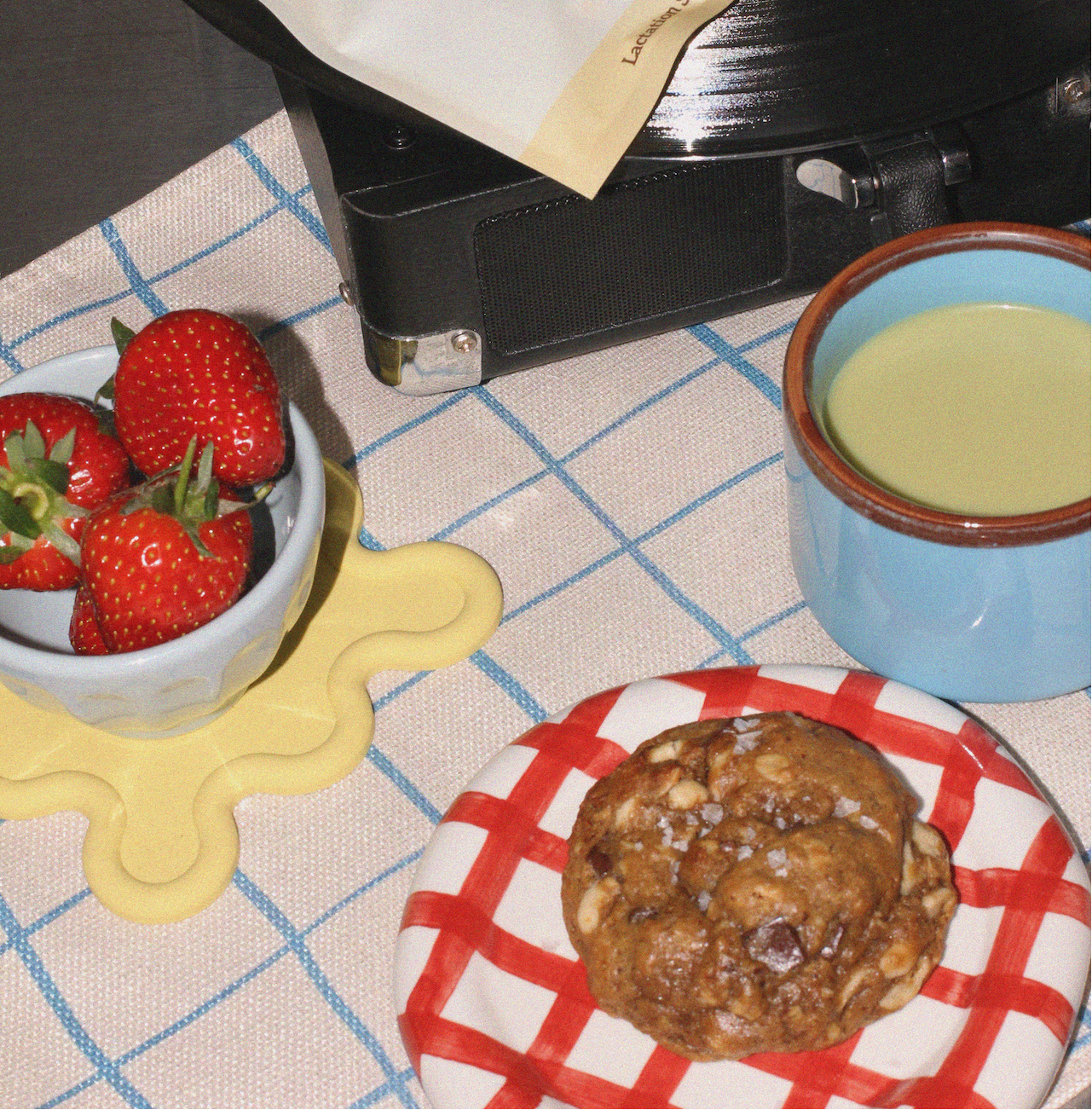 a vegan lactation support cookie on a plate with strawberries and a matcha 